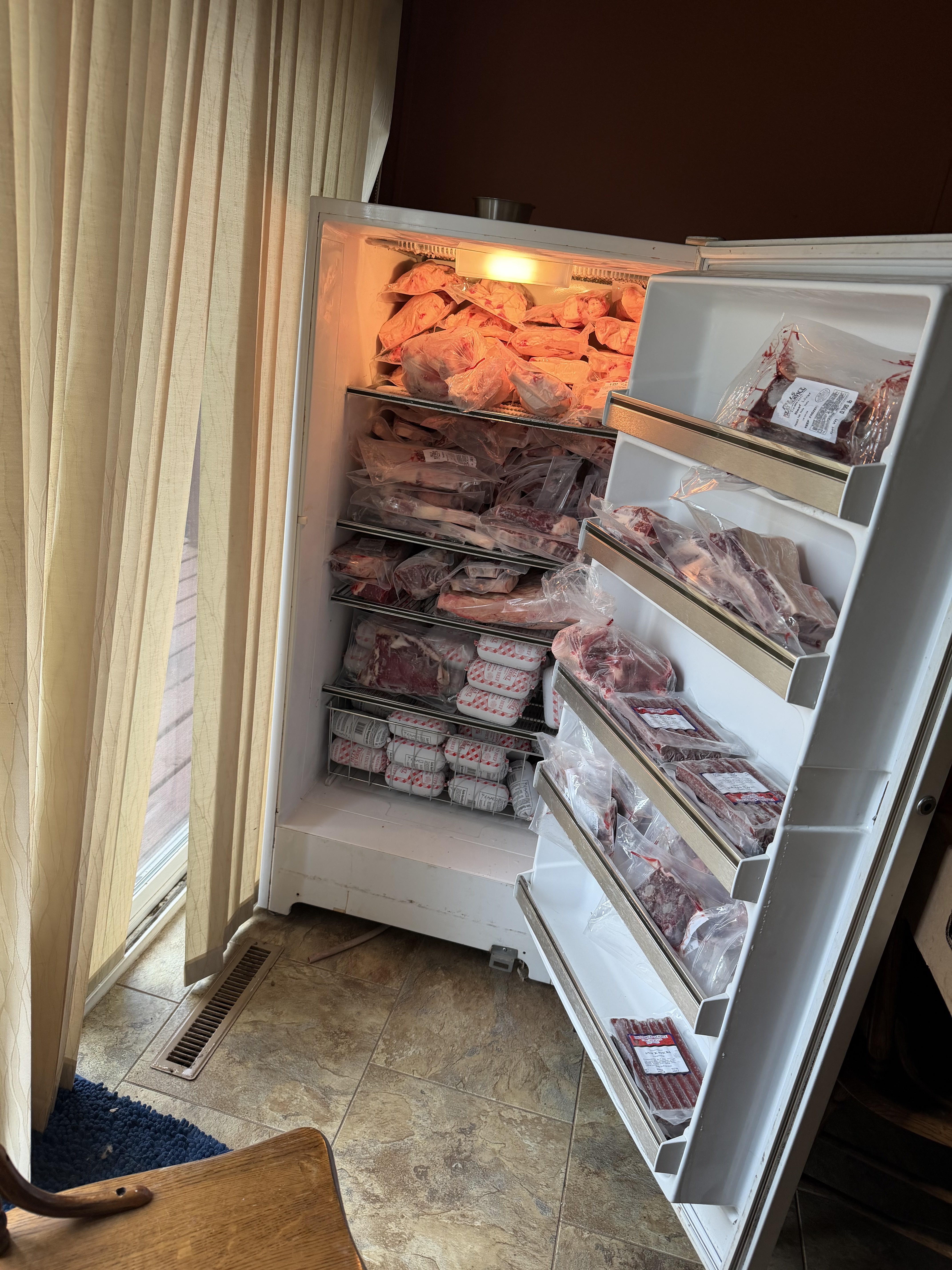 A chest freezer packed with wrapped beef cuts, ground beef, and snack sticks from our half of the steer